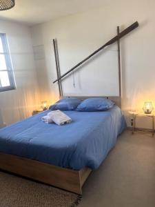 a bedroom with a large bed with blue sheets and blue pillows at Chaumière côtière: plage à 500m,à deux pas du GR34 in Plérin