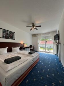 ein Hotelzimmer mit 2 Betten und einem Deckenventilator in der Unterkunft Air Muc Park Sleep & Fly in Hallbergmoos