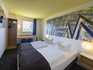 a hotel room with two beds and a mural on the wall at B&B Hotel Leipzig-Nord in Leipzig