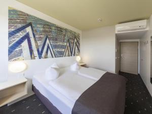 Un dormitorio con una cama blanca y una pintura en la pared en B&B Hotel Leipzig-Nord, en Leipzig