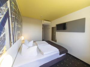 1 dormitorio con 1 cama blanca y TV de pantalla plana en B&B Hotel Leipzig-Nord, en Leipzig