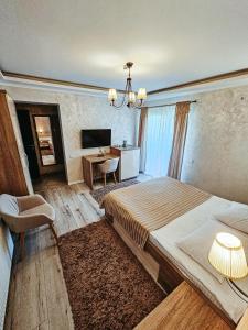 - une chambre avec un lit, un bureau et une télévision dans l'établissement Complex Hanul Cavalerului, à Onești