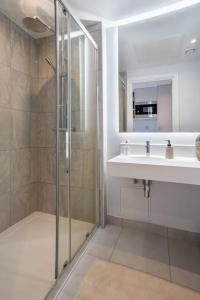 ein Bad mit einer Glasdusche und einem Waschbecken in der Unterkunft En-suite room in London