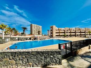 a swimming pool with a stone wall next to a building at El Horno in Adeje