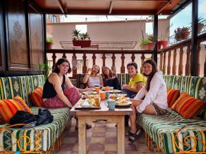 Eine Gruppe von Menschen, die an einem Tisch sitzen und Essen essen. in der Unterkunft Surf hostel Morocco in Tamraght Ouzdar