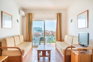 a living room with a couch and a tv at Apartamentos Turisticos Alagoa Praia in Altura