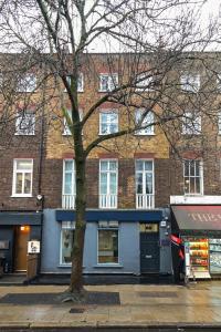 un grande edificio in mattoni con un albero di fronte di Charlotte Street Rooms by News Hotel a Londra