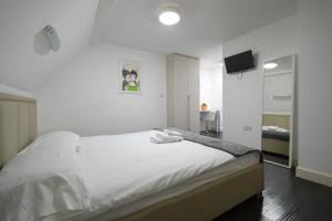 a white bedroom with a large bed with white sheets at Charlotte Street Rooms by News Hotel in London