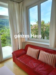 Sofá rojo en una habitación con ventana grande en FLORES, Ferienhaus oder Doppelzimmer, im Grünen, 5 Gehminuten ins Zentrum, Parkplatz, zero emissions en Bad Ischl