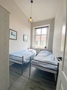 twee bedden in een kamer met een raam bij Ruim appartement in monumentaal gebouw in Vianen