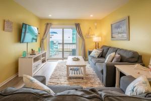 a living room with a couch and a tv at Oceanfront with Pool - Winds VI in Carolina Beach
