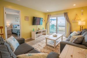 a living room with a couch and a tv at Oceanfront with Pool - Winds VI in Carolina Beach +28 photos