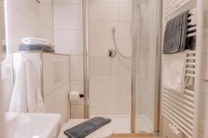 baño blanco con ducha y lavamanos en Seehus 8, en Norderney