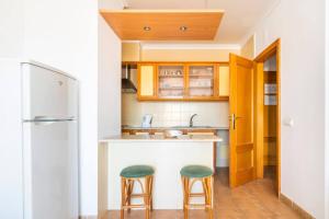 a kitchen with two bar stools and a refrigerator at Apartamentos Turisticos Alagoa Praia in Altura