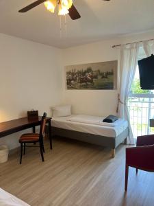 1 dormitorio con cama, escritorio y ventilador de techo en Air Muc Park Sleep & Fly, en Hallbergmoos