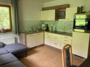 a kitchen with white cabinets and a couch at Blaserhof Hainzenberg in Hainzenberg