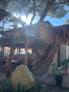 a log cabin with stairs and a tree at Calme Beach in Vlorë