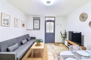 a living room with a couch and a tv at LE LOGY-COSY - Appartement 5 pers - Clim Wifi Cosy Garage in Saint-Gilles