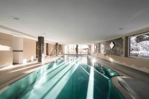 a swimming pool in a building with a large window at Genusshotel Fichtenhof in Grossarl