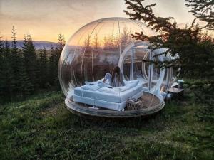 een vrouw in een glazen koepel in een veld bij Buubble Hotel - Ölvisholt in Selfoss