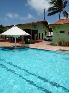 einem großen Pool mit Sonnenschirm vor einem Gebäude in der Unterkunft Pargos Club de Salinas in Salinópolis