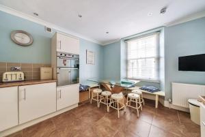 Una cocina con gabinetes blancos y una mesa y sillas. en Georgian Town House, en Ilfracombe