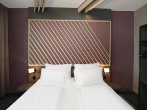 um quarto com uma cama com almofadas brancas em B&B Hotel Berlin City-Ost em Berlim