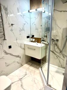 biała łazienka z prysznicem i umywalką w obiekcie Miracle Place w Iwano-Frankiwsku