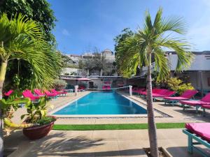 una piscina con palmeras y tumbonas rosas en Mui Ne Hills Bliss Hotel, en Mui Ne