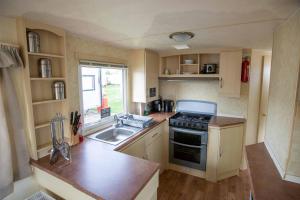 a small kitchen with a sink and a stove at Skegness Caravans in Skegness