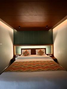 a bedroom with a large bed with a green headboard at Hotel City Palace in Ooty