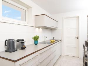 a white kitchen with white cabinets and a window at Kliffsand-72 in Kampen