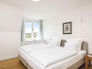 two beds in a white room with a window at Kliffsand-72 in Kampen