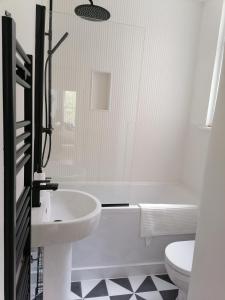 La salle de bains est pourvue d'une baignoire, d'un lavabo et de toilettes. dans l'établissement 2 Bed Apartment in Sydenham, London, à Forest Hill