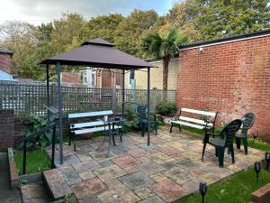 eine Terrasse mit Tischen, Stühlen und einem Sonnenschirm in der Unterkunft 116 Maison Dieu Road Room D in Dover in Kent