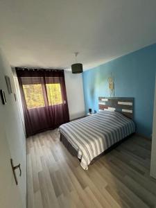 una camera da letto con letto, pareti blu e pavimenti in legno di T3 de charme proche du centre a Douai