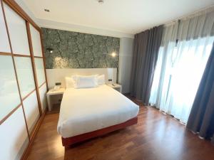 a bedroom with a white bed and a large window at Hotel San Fermín Pamplona in Burlada