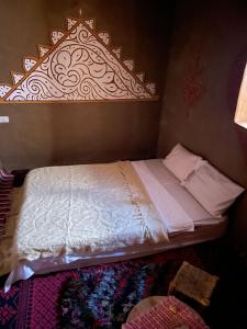 uma cama num quarto com uma cabeceira em madeira em Dar Laassri Tours em M'hamid