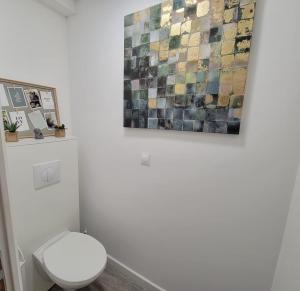 a bathroom with a toilet and a painting on the wall at Studio 6 in Le Boupère