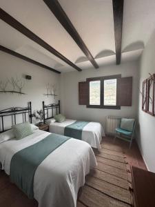 a bedroom with two beds and a chair and two windows at Casas Bajas Alojamiento Rural in Casas Bajas +10 photos