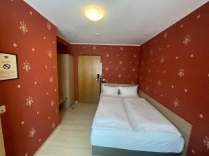 ein kleines Bett in einem Zimmer mit roten Wänden in der Unterkunft Hafner Hotel- Apartment in Stuttgart
