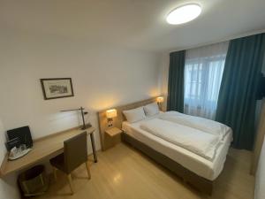 una camera con letto, scrivania e finestra di Hafner Hotel- Apartment a Stoccarda