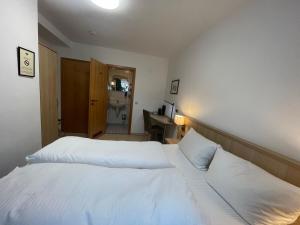 um quarto com uma cama com lençóis brancos e uma secretária em Hafner Hotel- Apartment em Stuttgart