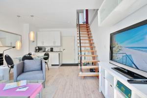 ein Wohnzimmer mit einem großen TV und einer Treppe in der Unterkunft Haus Adria Haus Adria Appartement 29 in Scharbeutz
