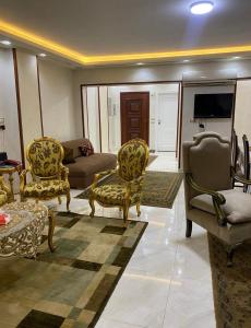 ein Wohnzimmer mit Stühlen, einem Sofa und einem TV in der Unterkunft شقة فندقية مميزة بالمنصورة in Ṭalkha