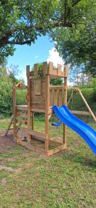 a wooden playset with a slide and a playground at Kékkút Cottage in Nagyvisnyó