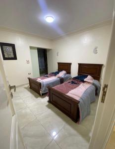 two beds are in a room with a tiled floor at شقة فندقية مميزة بالمنصورة in Ṭalkha