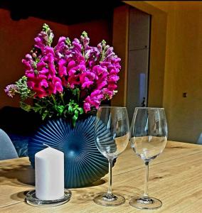 希馬拉的住宿－Philoxenia guest house，一张桌子,上面放有两杯酒杯和一个花瓶,上面放着紫色的花朵