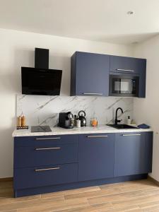 uma cozinha com armários azuis e uma bancada em Cosy Appart’ & spa - Appartement privatif - baignoire balnéothérapie 