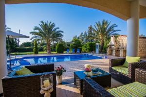 a patio with a pool and chairs and a table at GEORGIA BEACH VILLA in Argaka